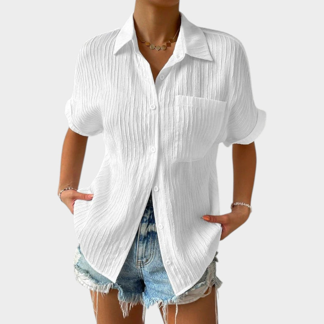 Woman wearing white textured button-up shirt paired with denim shorts