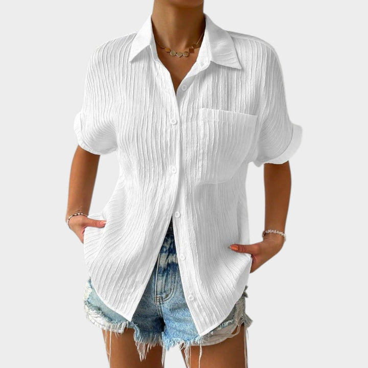 Woman wearing white textured button-up shirt paired with denim shorts