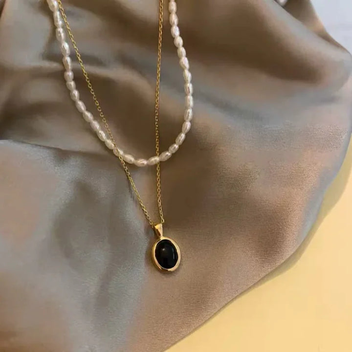 Layered pearl and gemstone necklace set displayed on silk fabric