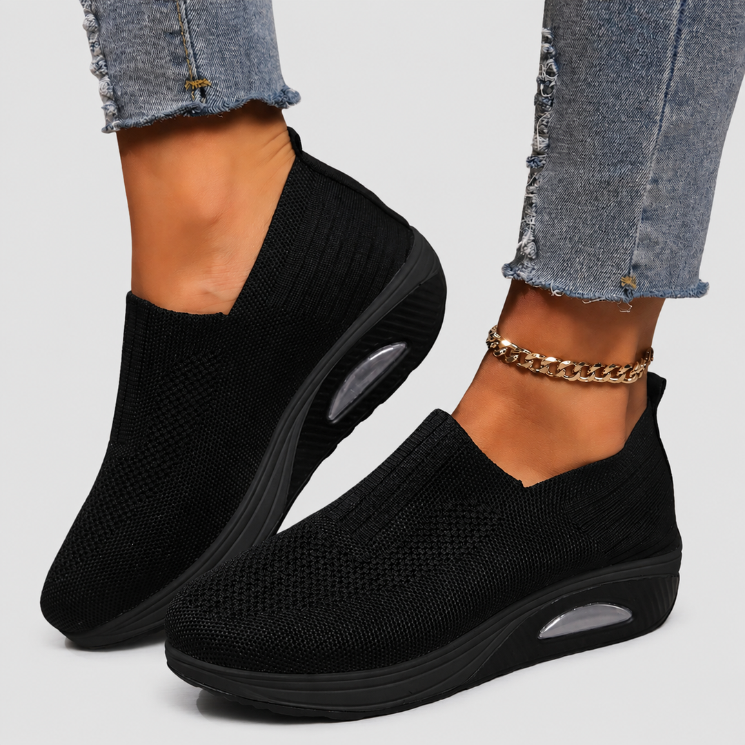 Close-up of black slip-on comfort shoes worn with distressed jeans