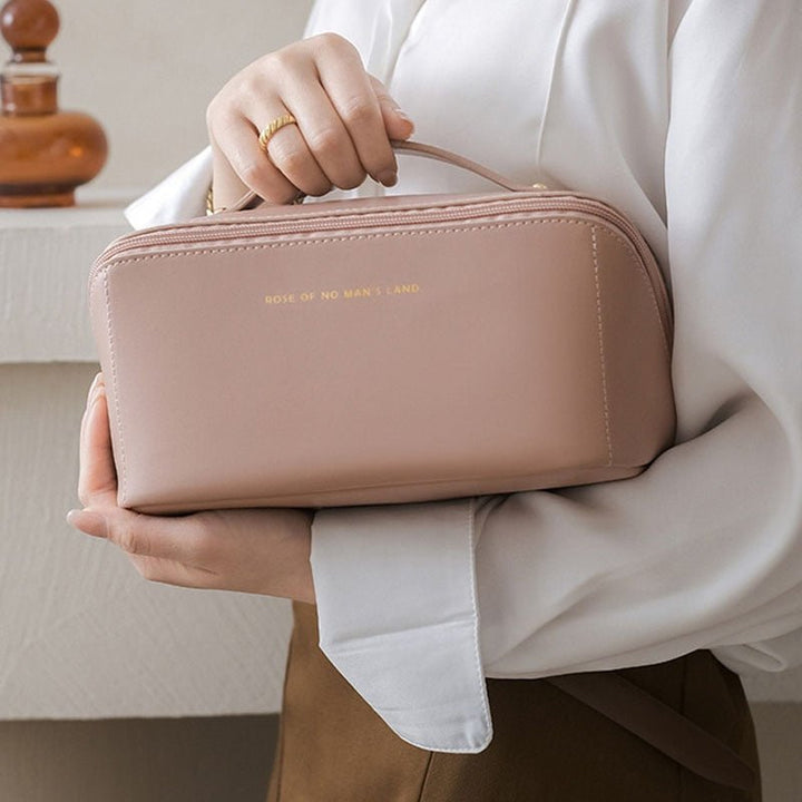 Woman holding a pink cosmetic travel bag by the handle