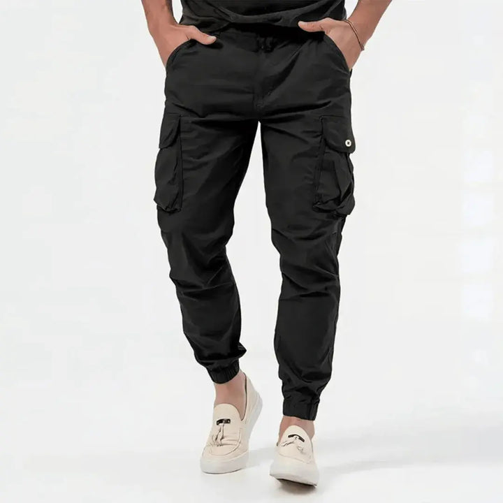 Man wearing black Fenix cargo jogger tapered pants with snap pockets