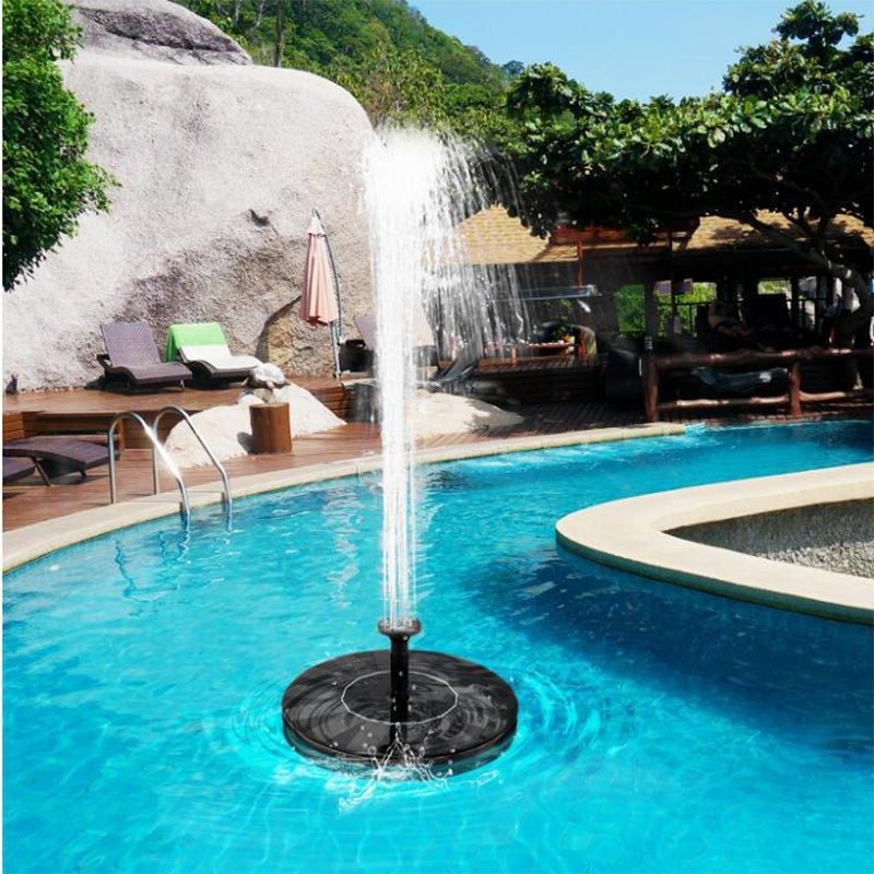 Floating solar fountain operating with a high water jet in a pristine outdoor swimming pool surrounded by deck chairs and tro