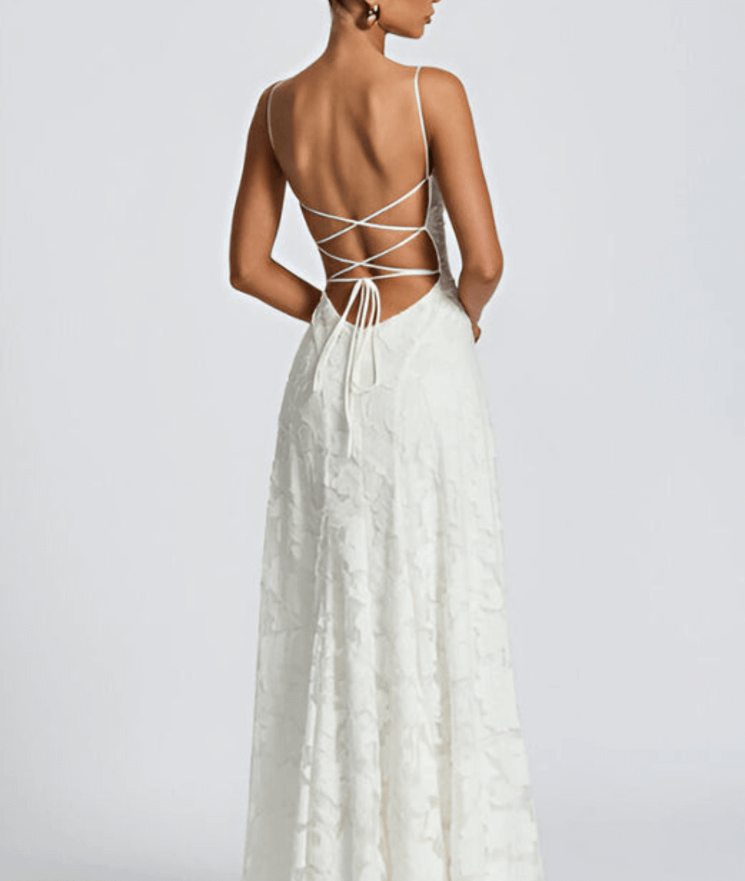 Back view of a woman wearing a white floral maxi dress with lace-up tie detail