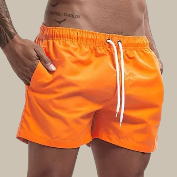 Close-up of bright orange men's regular fit swim shorts with elastic waist