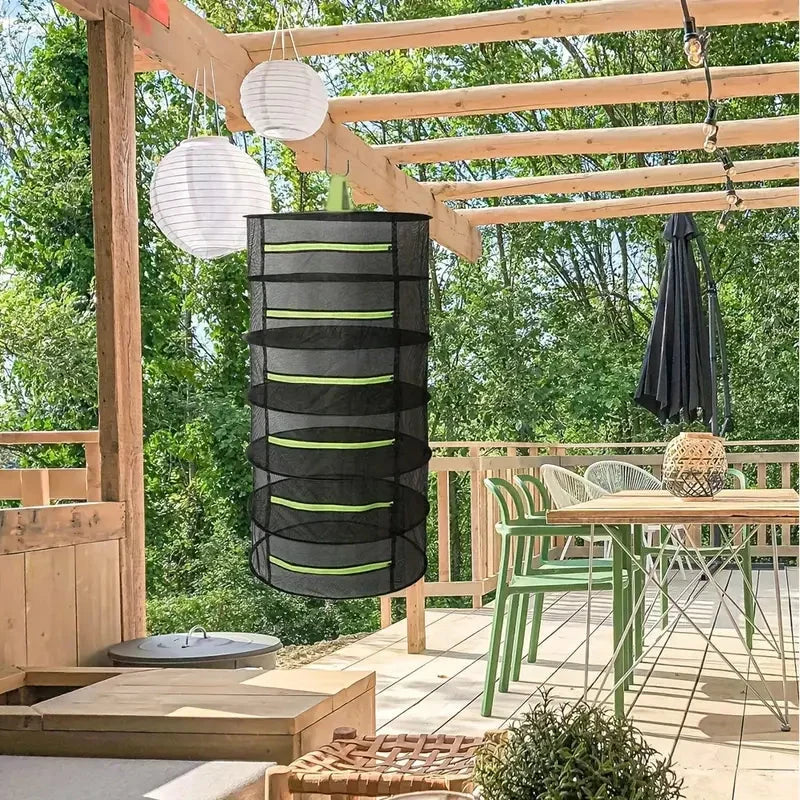 Multi-tier mesh hanging dryer being loaded with fresh herbs and plants
