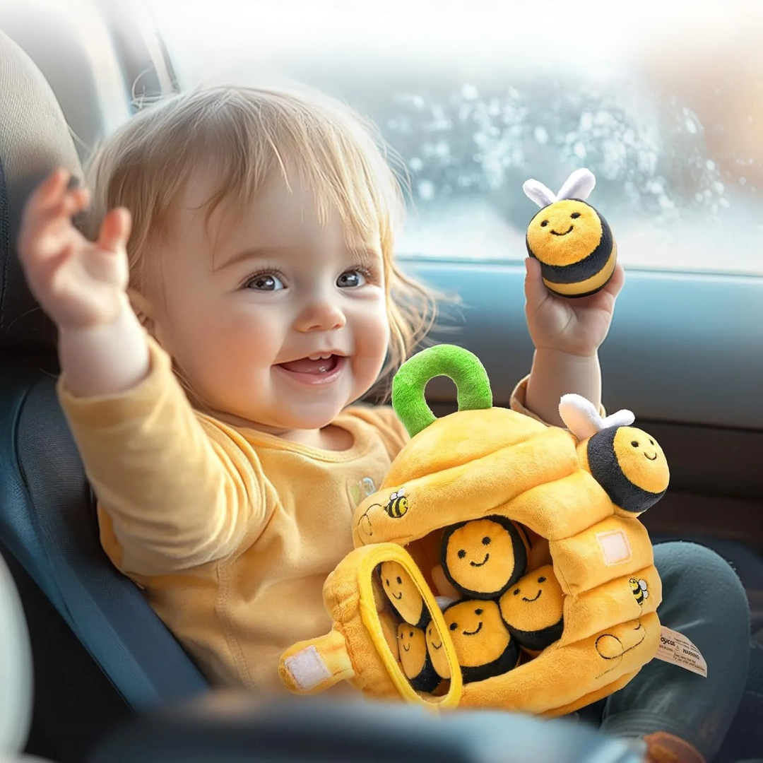 Happy toddler holding the beehive sensory plush toy in a car