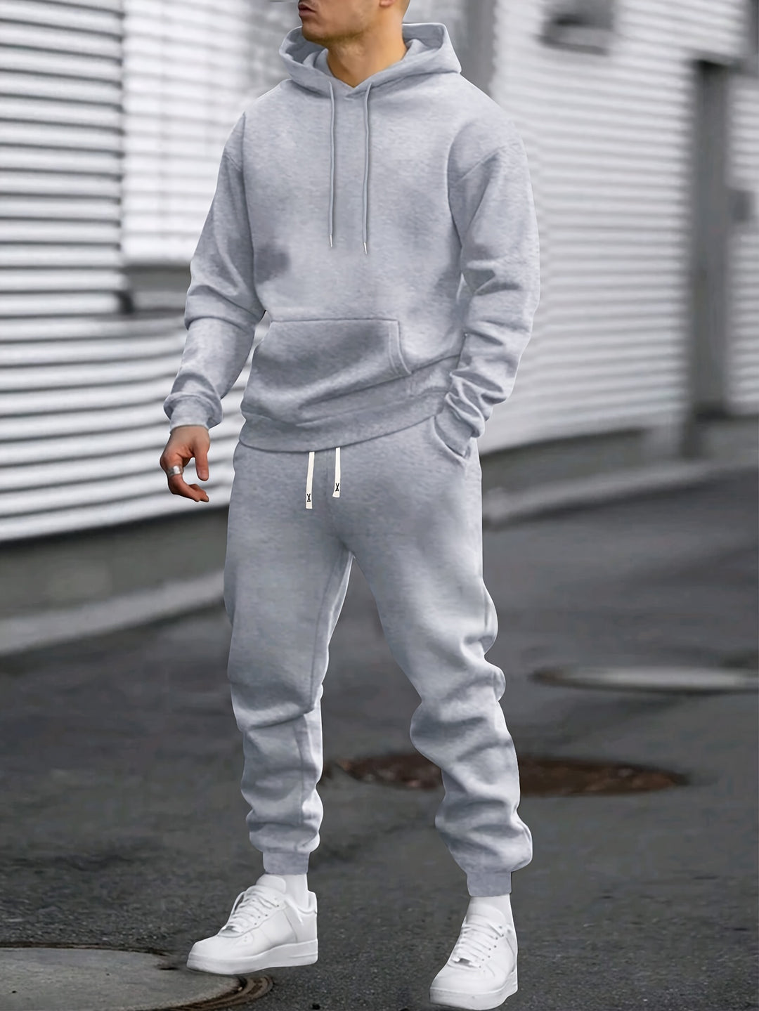 Man wearing grey men's sports set hoodie and jogging bottoms outdoors