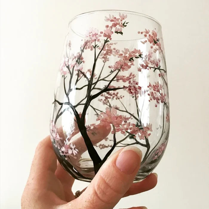 Detailed view of hand-painted seasonal tree motifs on stemless wine glasses