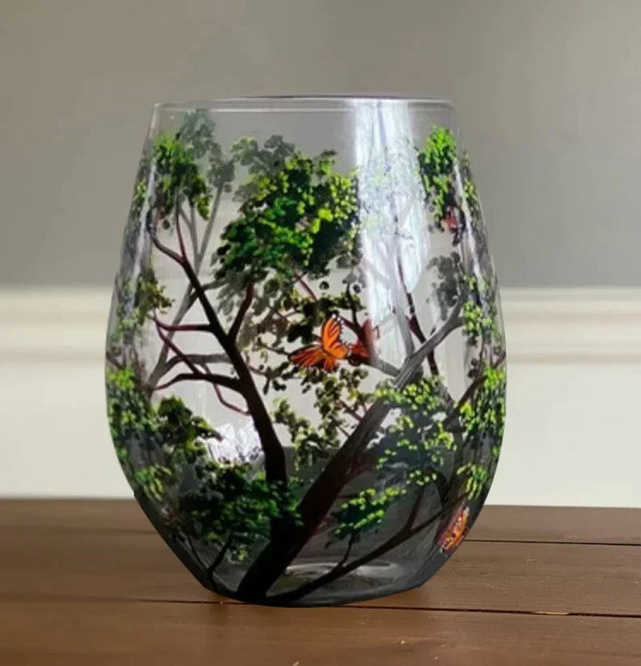 A single stemless hand-painted Summer tree wine glass showing lush green foliage