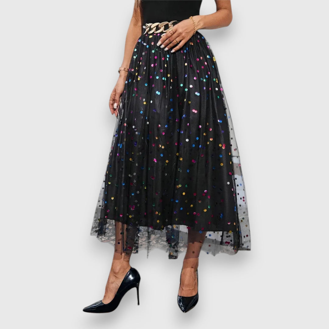 Close-up of multicolored polka dot mesh midi skirt paired with black heels