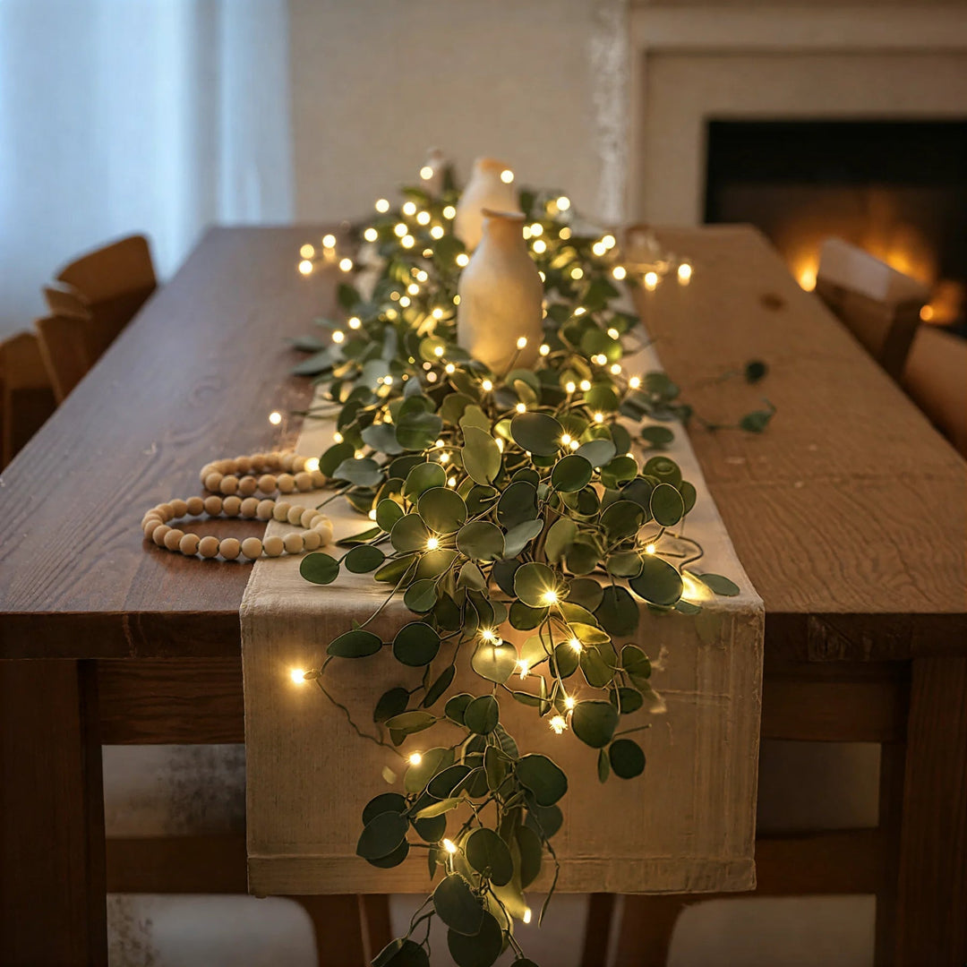 Illuminated olive branch garland decorating a wooden dining table runner