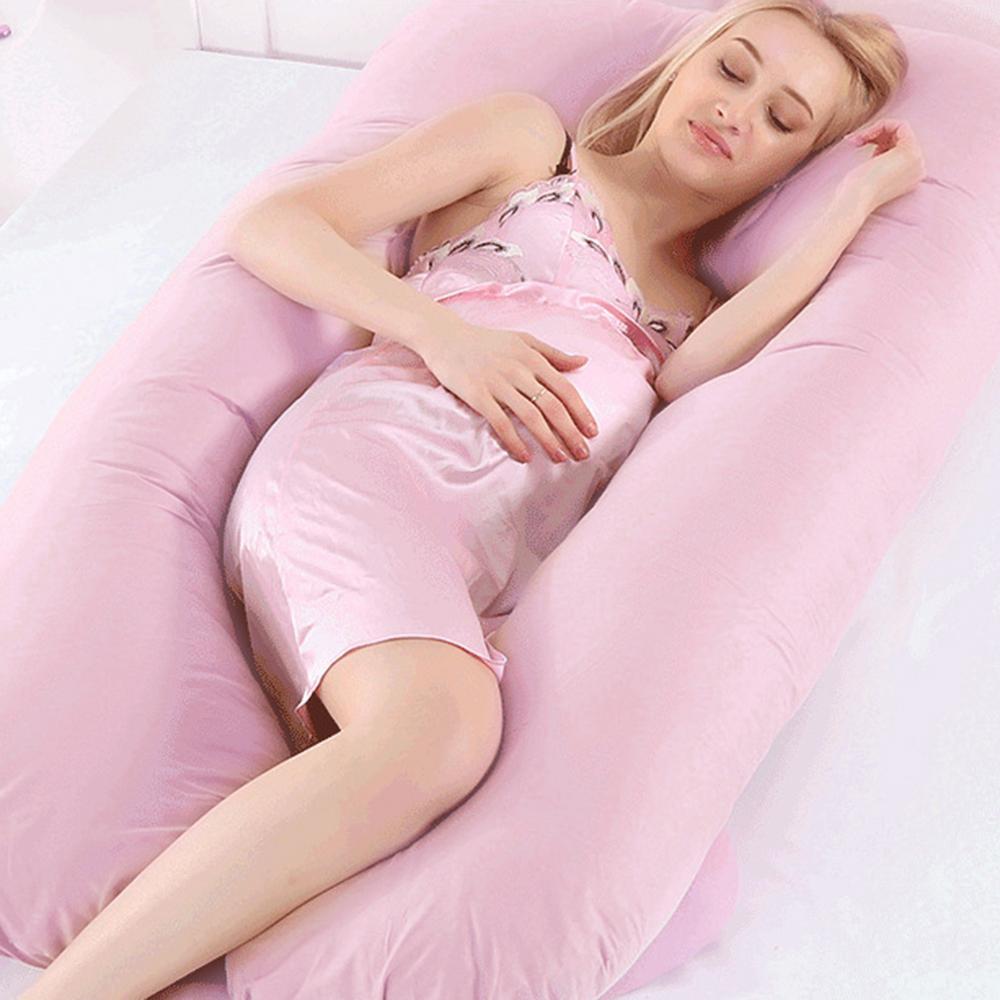 U-shaped sleeping pillow arranged on a queen size bed for lumbar support