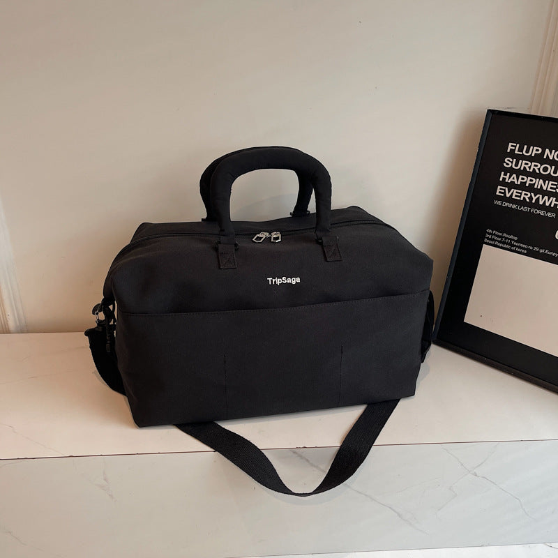 Black functional travel duffle bag with padded handles and adjustable shoulder strap
