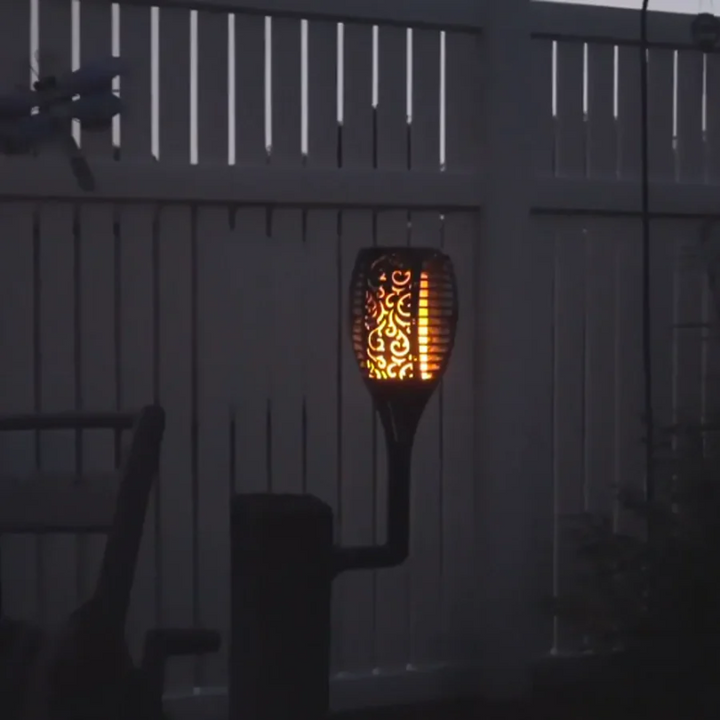 Solar flame torch mounted on a fence providing evening accent lighting