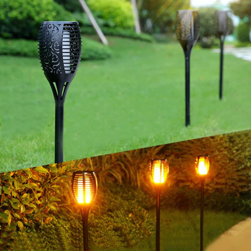 Solar flame garden torches glowing in a green lawn