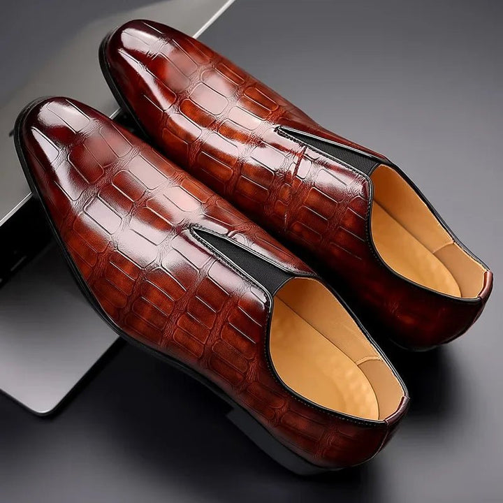 Side profile of men's brown dress loafers showing slip-on design and glossy finish.