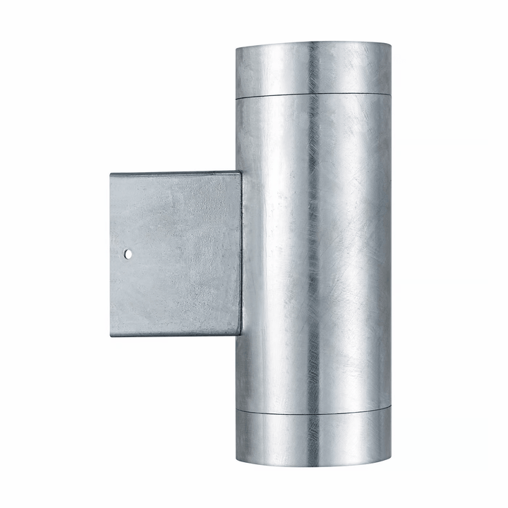 Modern silver up-down outdoor wall lamp illuminating exterior house facade with warm light