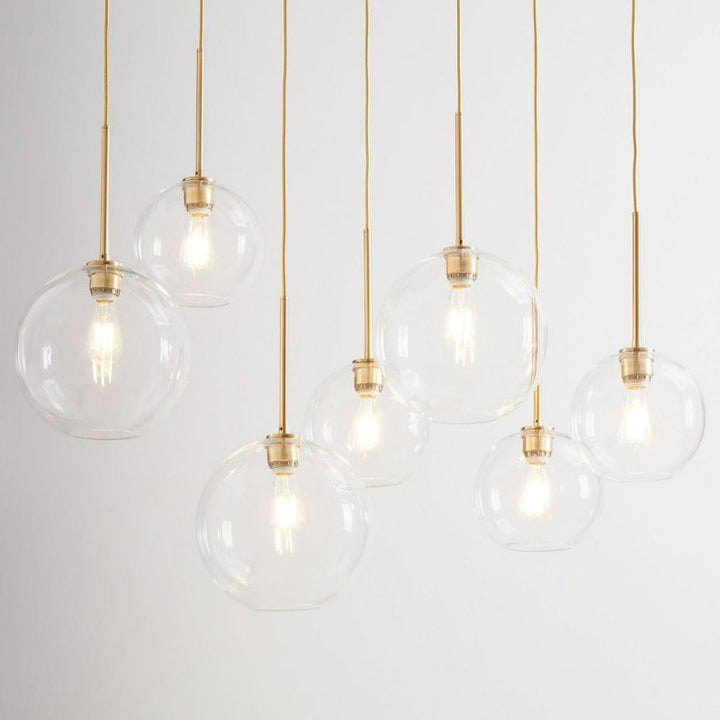 Minimalist indoor lighting fixture featuring a clear glass globe and metal accents