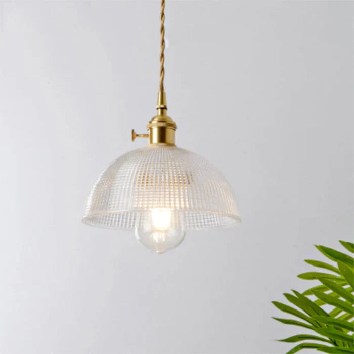 Clear textured glass dome pendant light hanging against a white wall
