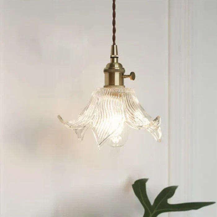 Transparent glass pendant lamp with flared floral shade design illuminating a room