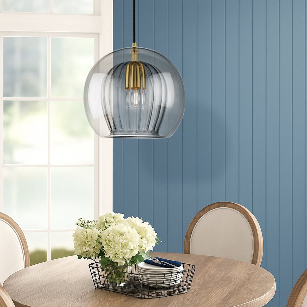 Smoke gray glass pendant light illuminating a dining area with blue wall paneling