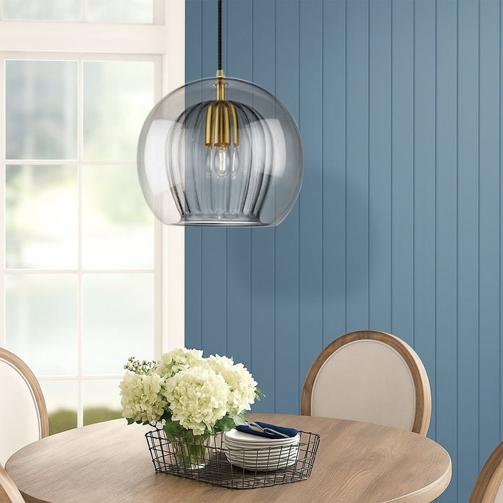 Smoke gray glass pendant light illuminating a dining area with blue wall paneling
