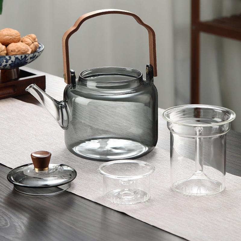 Disassembled glass teapot showing the main body, glass infuser, and wooden lid