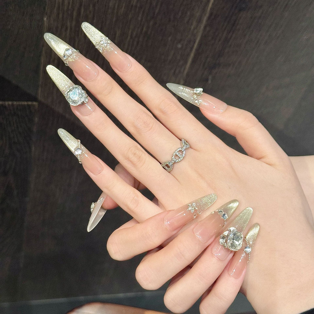 Close-up of woman's hands wearing long glittering press-on nails with rhinestone accents