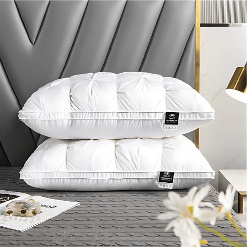 Two fluffy white goose down pillows stacked neatly on a grey patterned bed