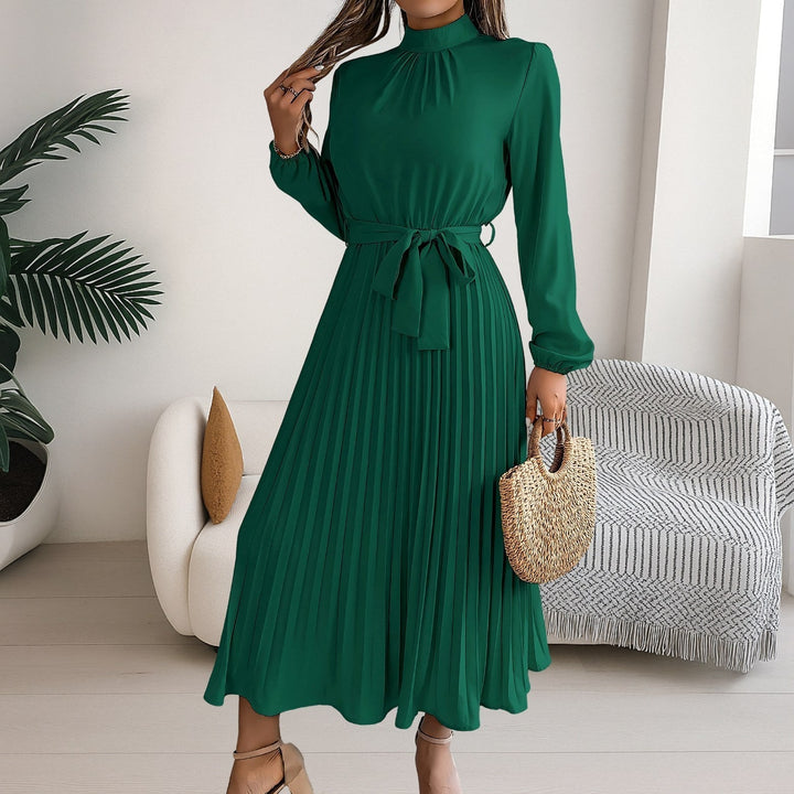 Front view of a woman wearing a dark green pleated midi dress with a tie belt