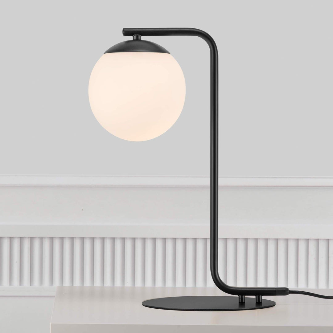 Modern black table lamp with opal glass sphere on a white surface