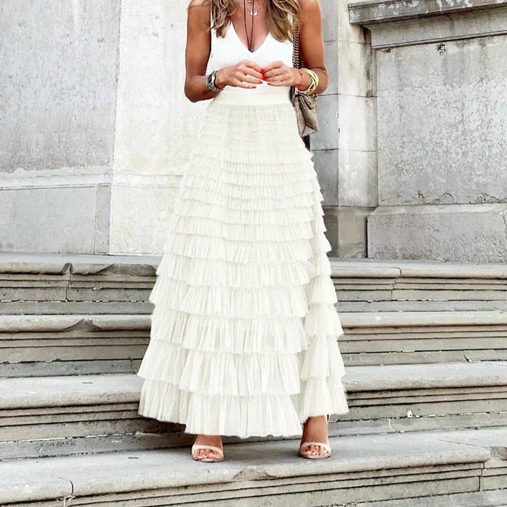 Woman wearing the Gwen high-waisted tiered maxi skirt in white on stone steps