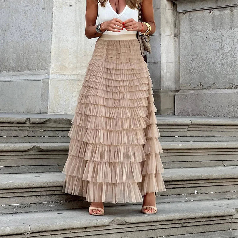 Woman wearing the Gwen high-waisted tiered maxi skirt in khaki paired with a white top