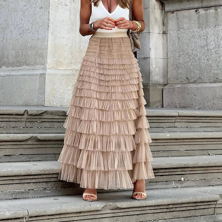 Woman wearing the Gwen high-waisted tiered maxi skirt in khaki paired with a white top