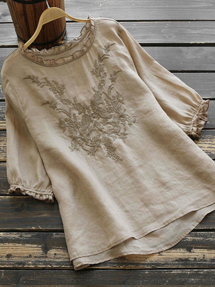 Women's beige boho embroidered blouse displayed on wooden surface