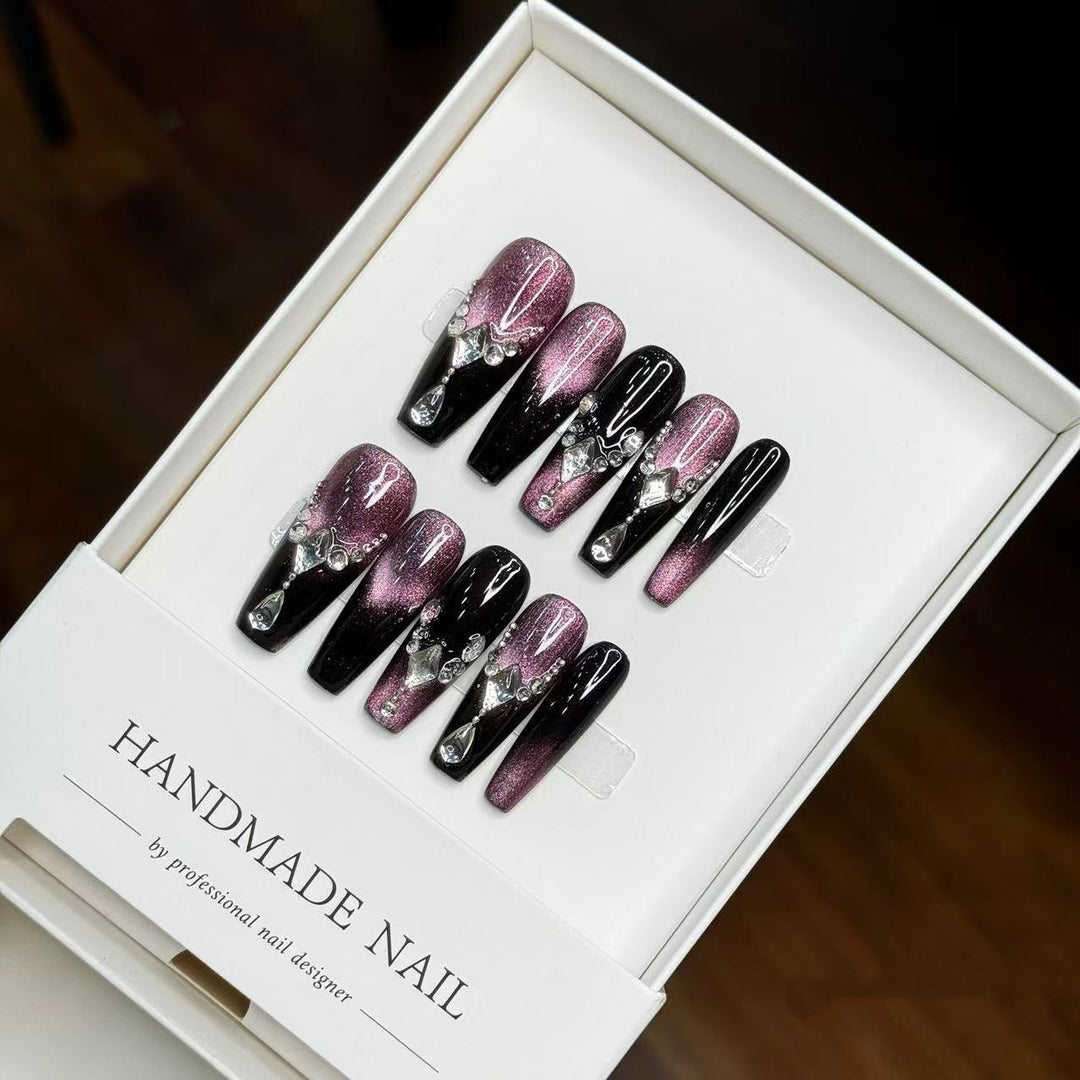 Handmade press-on nail art set in purple with gemstone accents inside a white box