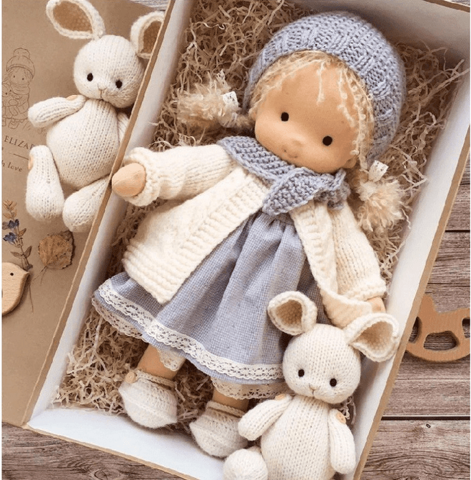 Back view of plush Waldorf baby doll showing attached hood and soft outfit