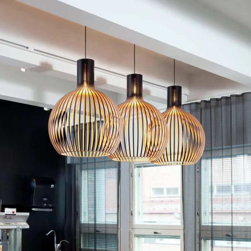 Three wooden pendant lamps with black accents hanging over a modern kitchen counter