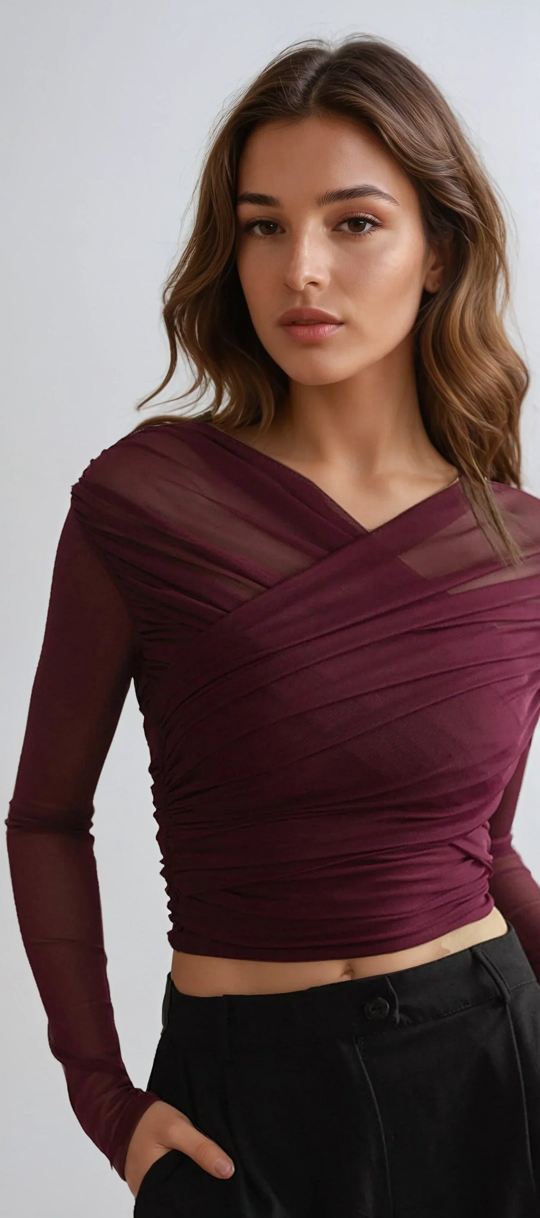 Woman wearing a dark red ruched cross wrap top with sheer long sleeves