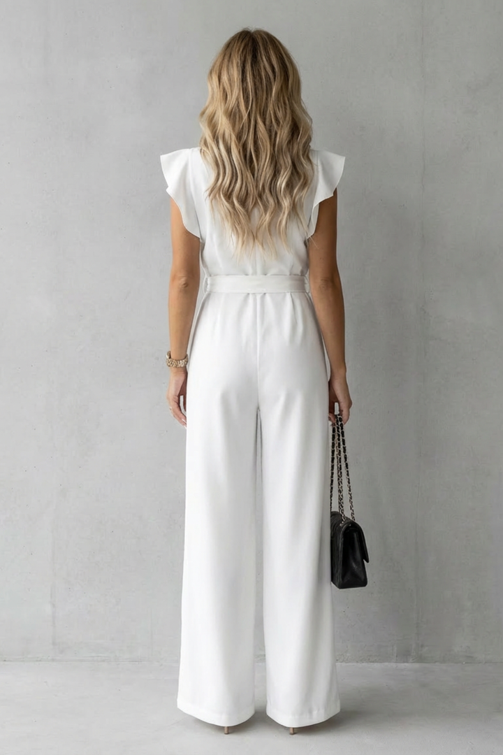 Back view of a woman showcasing the flowing floor-skimming wide-leg silhouette of the white jumpsuit.