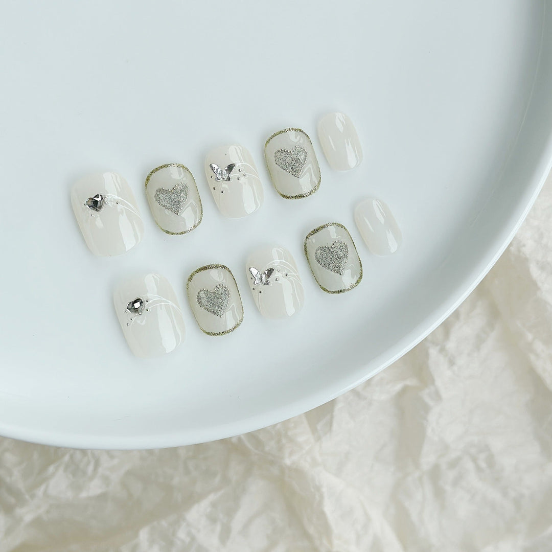 Heart-embellished press-on nail set with sparkling accents on white plate
