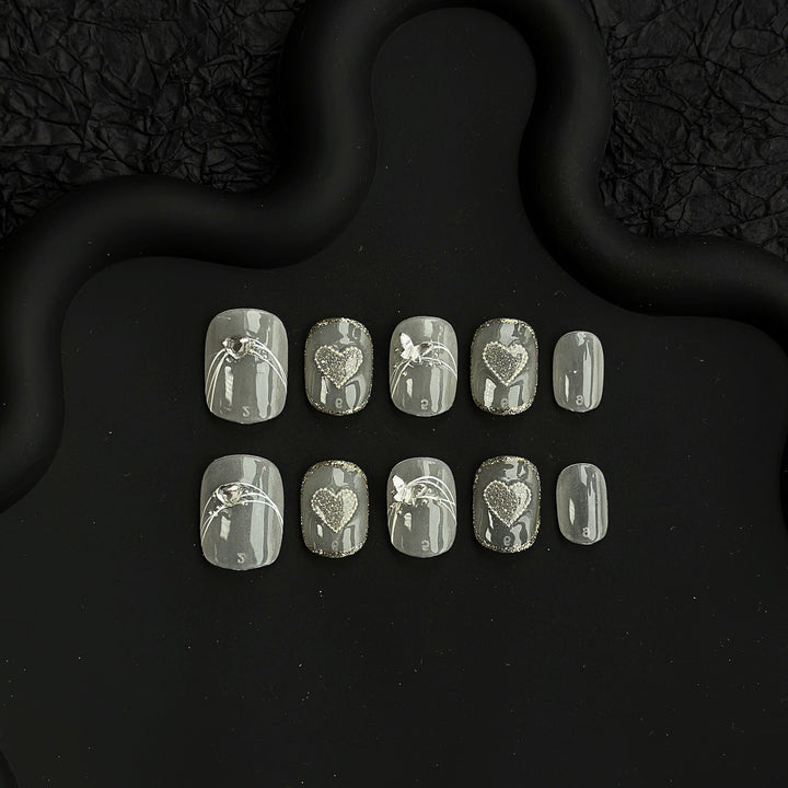 Press-on nail set showing various sizes and heart details on black background