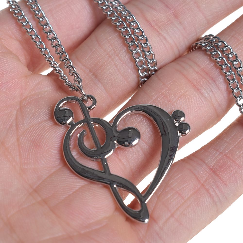Silver musical heart pendant necklace held in hand