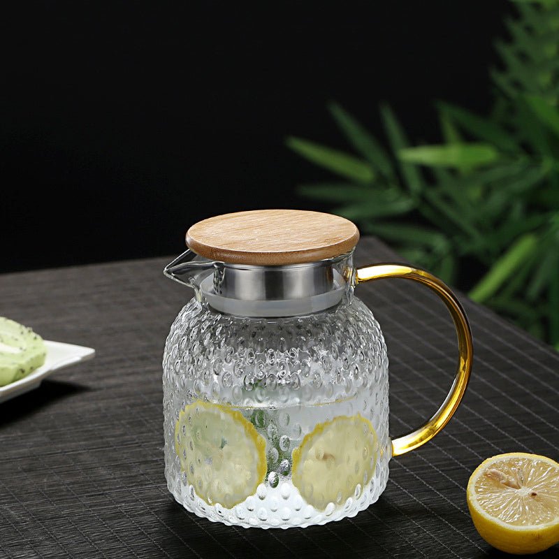 Heat-resistant textured glass pitcher filled with water and lemon slices with a bamboo lid