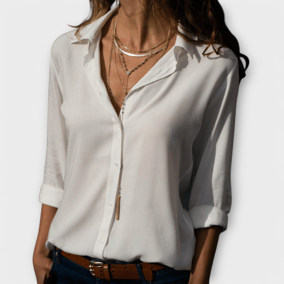 Woman wearing a white collared button down blouse with layered necklaces