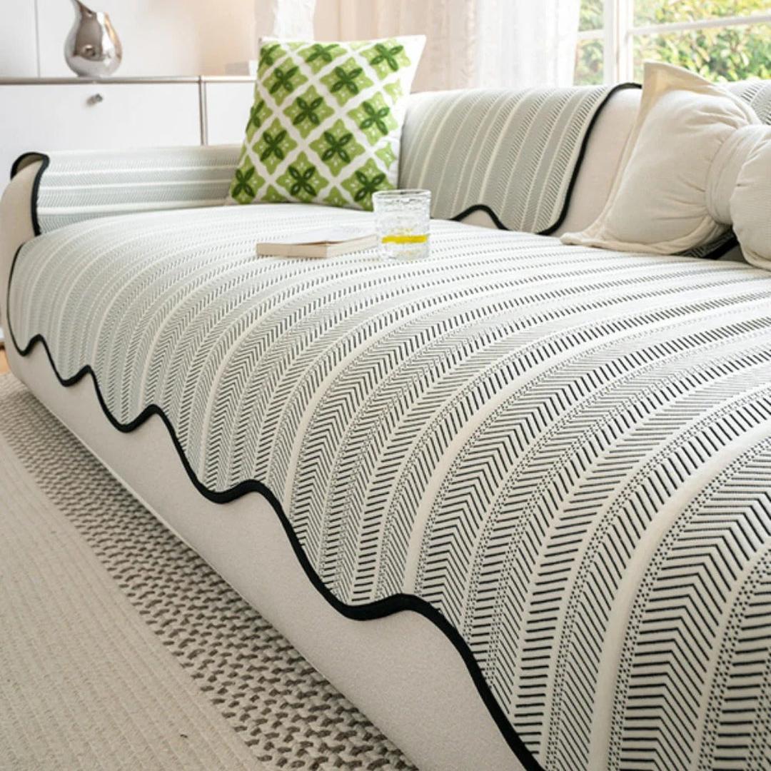 Close-up of herringbone sofa cover with black edge and scalloped trim on a modern couch
