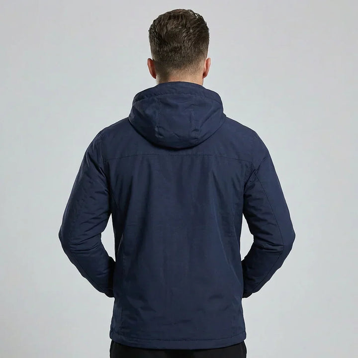 Back view of a man wearing a dark blue waterproof outdoor jacket with hood