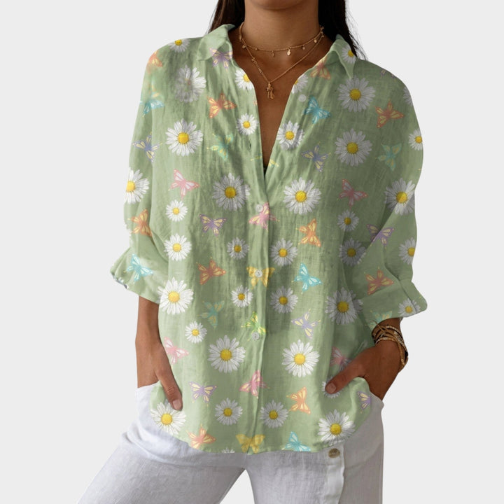 Woman wearing a sage green floral and butterfly print button-up blouse.