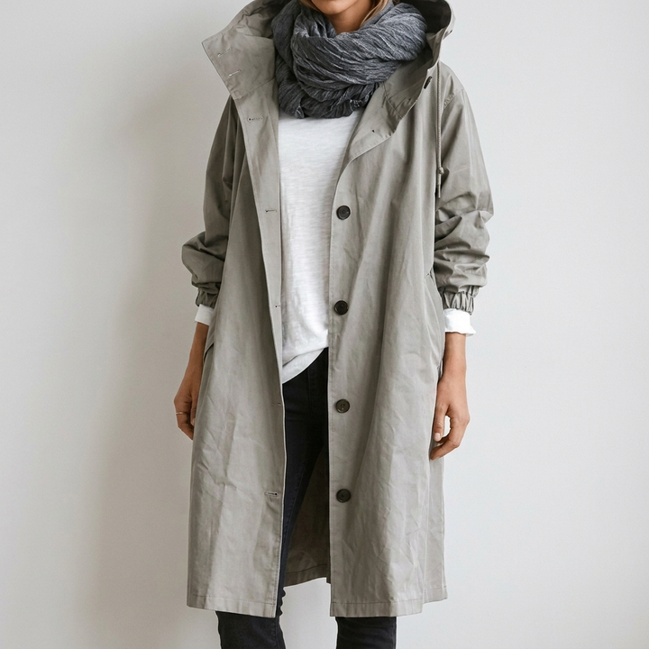 Woman wearing grey hooded waterproof raincoat with button front